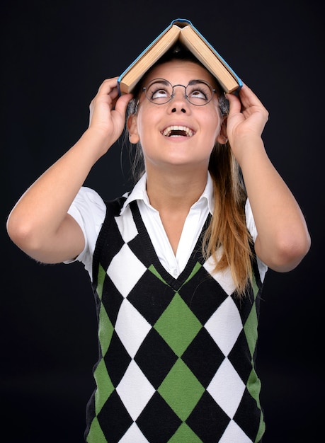 La fille à lunettes met un livre sur sa tête.