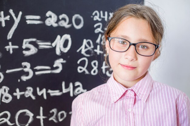 La fille à lunettes se tient près de la commission scolaire.