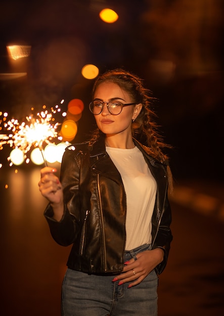 Fille avec des lunettes et sparkler sur la route le soir