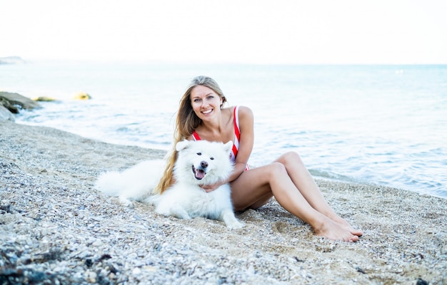 Fille en maillot de bain avec un chien sur la plage