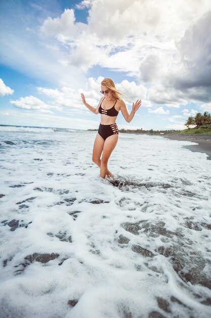 Fille en maillot de bain debout dans la vague de la mer