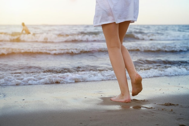 Fille en maillot de bain joue sur la plage avec une vague de mer qui saute en s'amusant