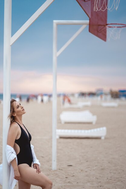 une fille en maillot de bain noir et une chemise blanche à l'aire de jeux sur la plage