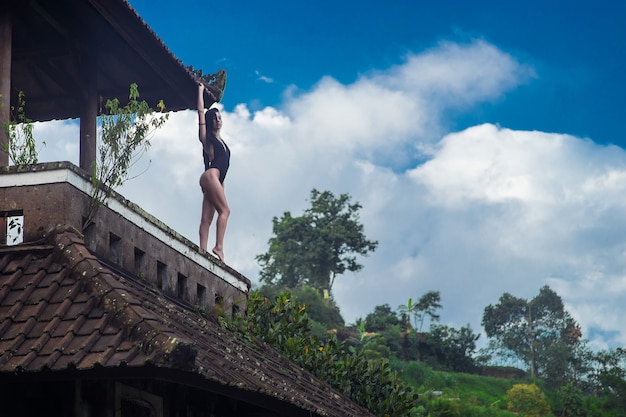 Fille en maillot de bain rester sur le toit dans le mystique hôtel pourri abandonné à Bali avec un ciel bleu. avec un ciel bleu