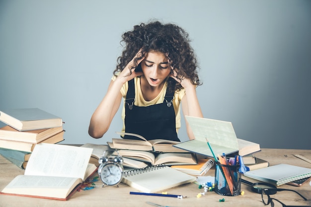 Fille Main Dans Les Cheveux Avec Des Livres Sur Le Bureau