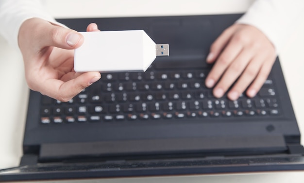 Fille main tenant une clé USB à l'aide d'un ordinateur portable.