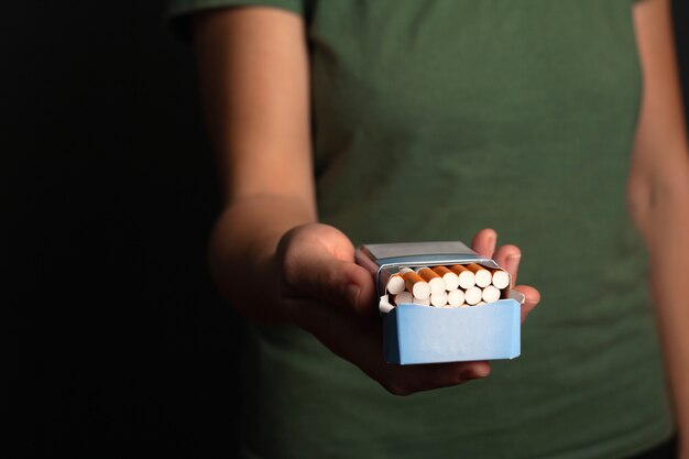 Fille de main tient un paquet de cigarettes suggère de faire un choix. offrir de la nicotine, du tabac.