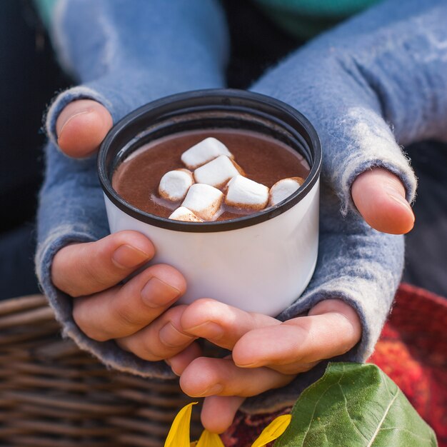 Fille mains tenant une tasse de chocolat chaud ou de cacao avec marshmal