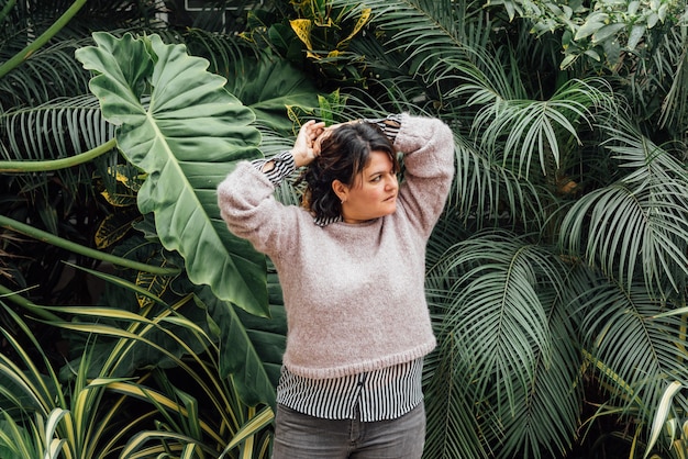 Fille avec les mains sur la tête et regarde de côté avec fond de foi feuillage