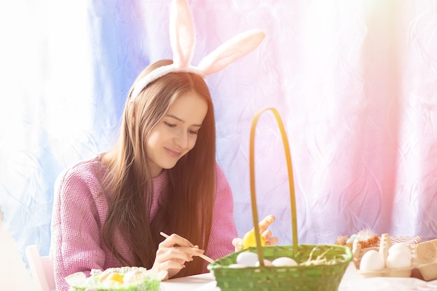 Photo une fille à la maison se prépare pour la famille pâques décore des œufs de fête pour la chasse porte des oreilles de lapin