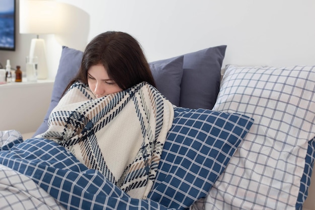 Fille malade en couverture sur oreiller dans la chambre