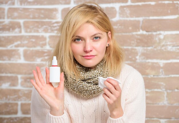 Une fille malade tient des gouttes nasales et des tissus. Notion d'allergie. Traitement à domicile. Bouteille en plastique de gouttes nasales. Spray nasal efficace. Nez qui coule et autres symptômes du rhume. Spray nasal remède nez qui coule.