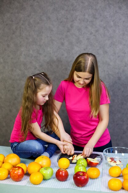 Fille et maman ont coupé une salade de fruits composée de pomme orange et de mandarine