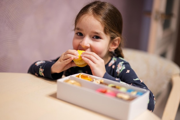 Fille mange de délicieux macarons de couleur douce et savoureuse