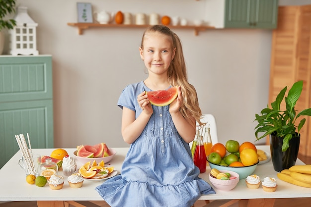 Fille mange des fruits à la cuisine