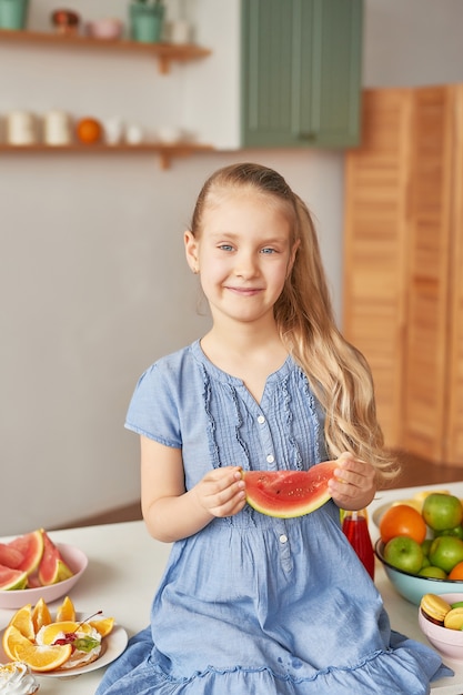 Fille mange des fruits à la cuisine