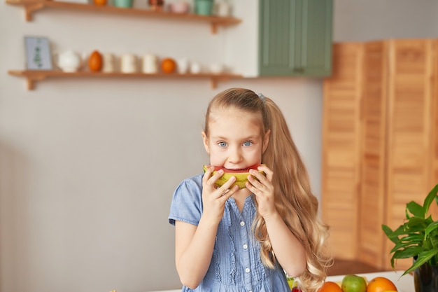 Fille mange des fruits à la cuisine