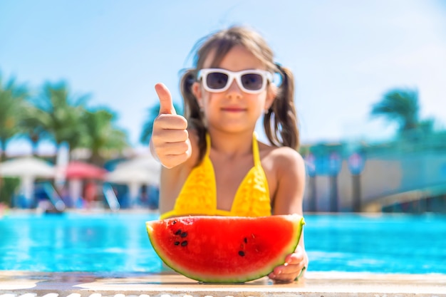 La fille mange la pastèque à l'intérieur de la piscine