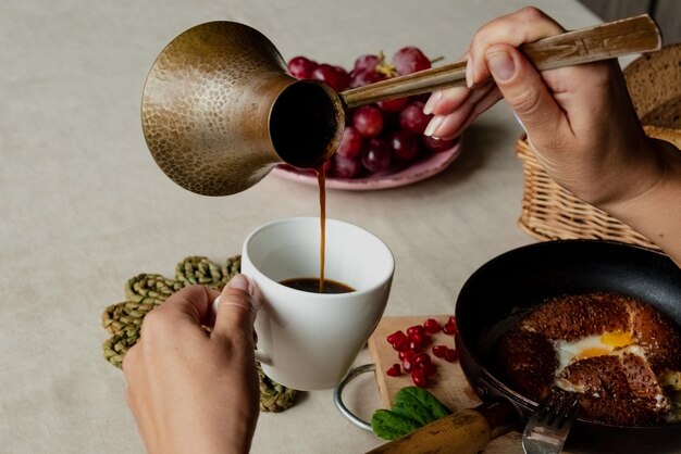 Fille mange le petit déjeuner et verse le café d'un turc