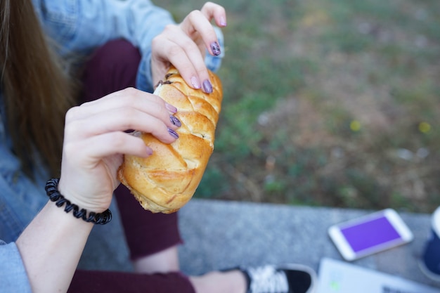 Fille mange des petits pains au chocolat dans la rue