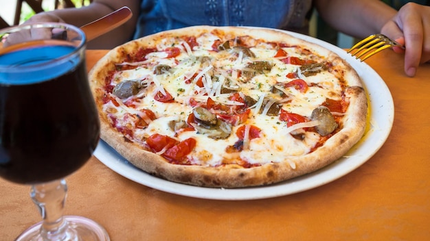 La fille mange de la pizza avec des champignons au restaurant