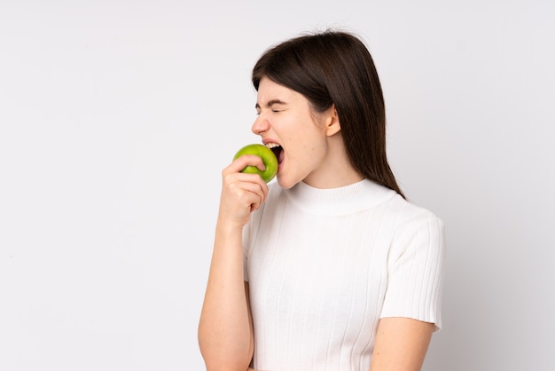 Fille mange une pomme sur le mur