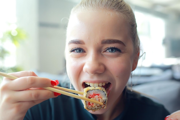 fille mange des sushis et des petits pains dans un restaurant / cuisine orientale, cuisine japonaise, jeune mannequin dans un restaurant