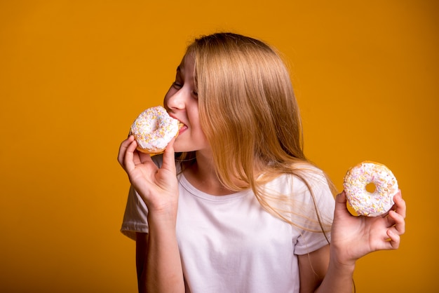 Fille mangeant des beignets sur fond jaune