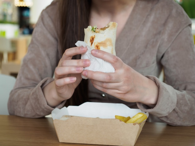 Fille mangeant de la restauration rapide dans un restaurant se bouchent