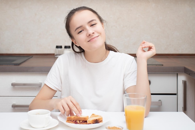 Fille mangeant un sandwich le matin pour le petit déjeuner et buvant du café aromatique