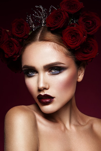 Fille de mannequin de beauté avec maquillage sombre et roses dans les cheveux