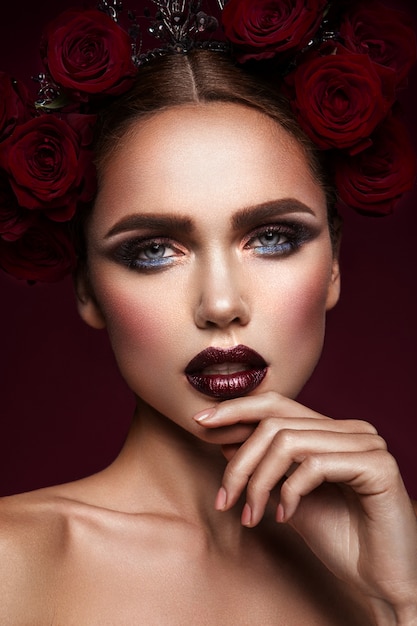 Fille de mannequin de beauté avec maquillage sombre et roses dans les cheveux