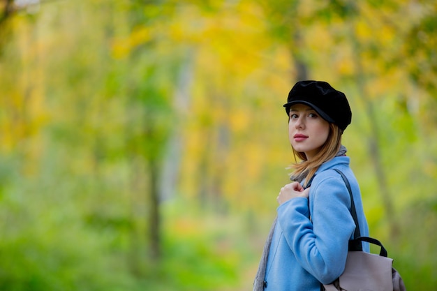 Fille en manteau et chapeau dans un parc.