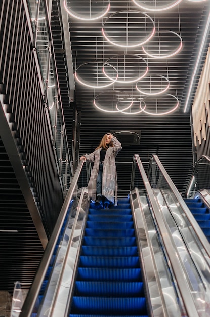 une fille en manteau descend l'escalator