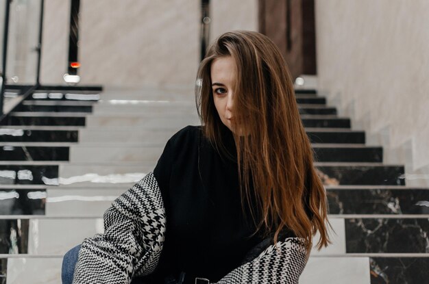 une fille en manteau est assise dans les escaliers