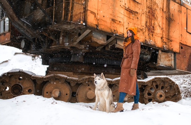 Fille en manteau marron et assis à côté de chien husky