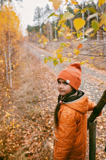 Fille en manteau orange se promène dans la forêt d'automne en pensant à la santé mentale automne vibes mode de vie en plein air