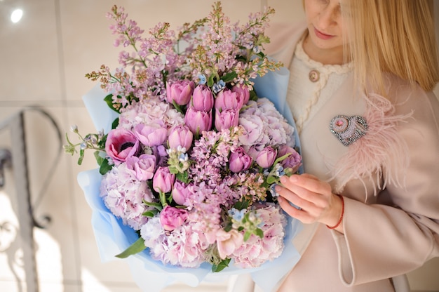 Fille en manteau regardant le bouquet de tulipes violettes violettes et lilas