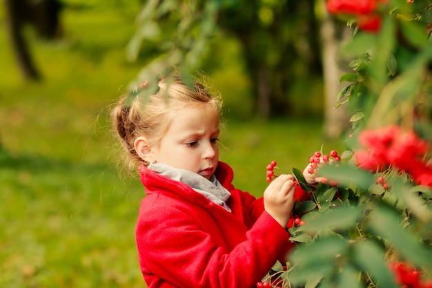 fille en manteau rouge avec les feuilles de l'automne dans le parc.