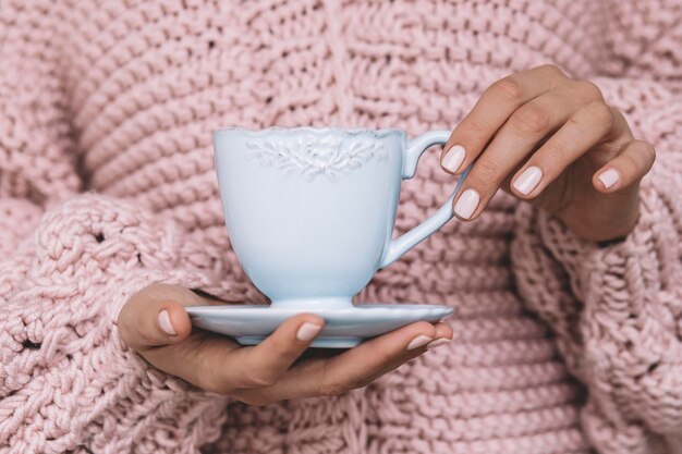 Fille avec manucure rose tenant la tasse.