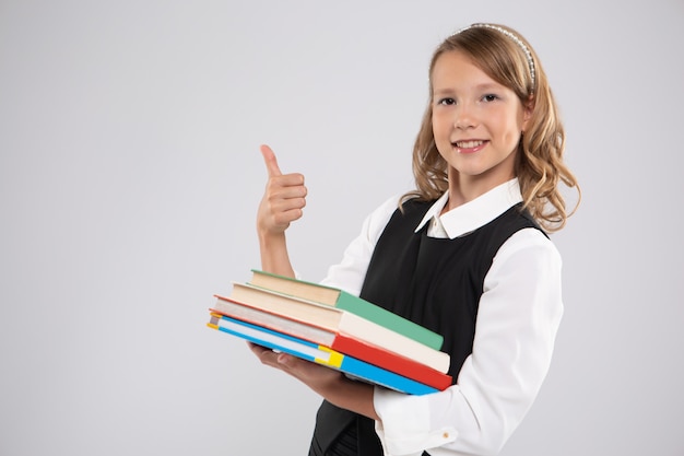 Fille avec manuels montre un signe de classe.