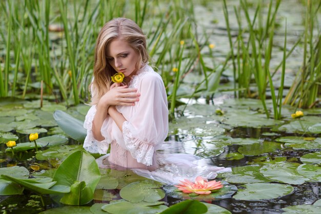 Fille avec un maquillage doux dans le lac parmi les lotus et les nénuphars