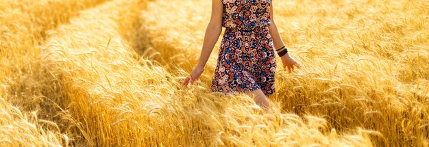 Fille marchant dans le champ d'or et touchant un blé avec sa main
