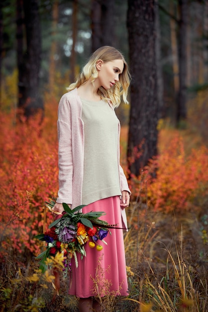 Fille marchant dans la forêt d'automne. Un grand beau bouquet de fleurs dans les mains d'une femme.