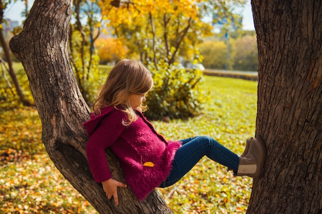 Fille marchant dans le parc parmi les arbres et les feuilles jaunes tombant en automne