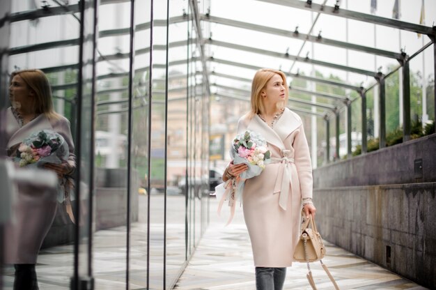 Fille marchant dans la rue tenant un beau bouquet de couleur rose