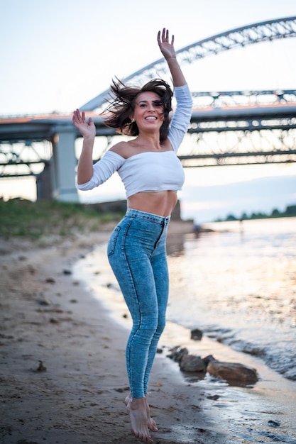 Fille marchant sur la plage contre le coucher du soleil