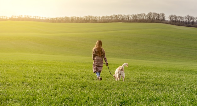 Fille marche chien sur champ vert