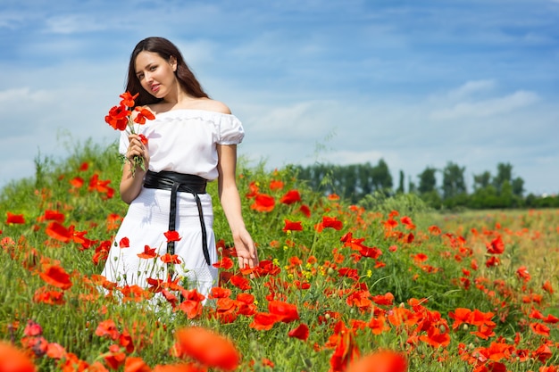 Fille marche dans un champ de coquelicots