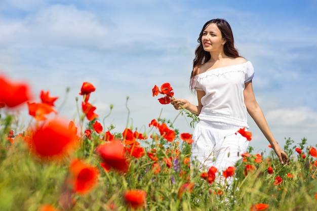 Fille marche dans un champ de coquelicots